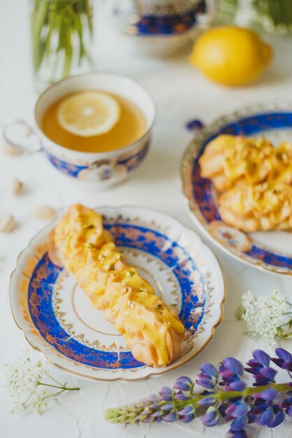 Eclairs de limón y té de limón en un juego de té vintage y flores en blanco