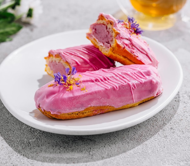 Eclairs mit rosa Glasur und Tee