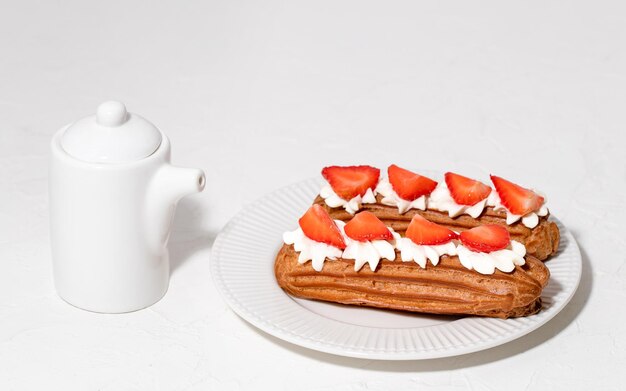 Foto eclairs mit sahne und erdbeeren auf einem weißen teller