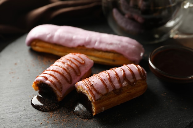 Eclairs sabrosos con deliciosa cobertura en bandeja negra, cerrar