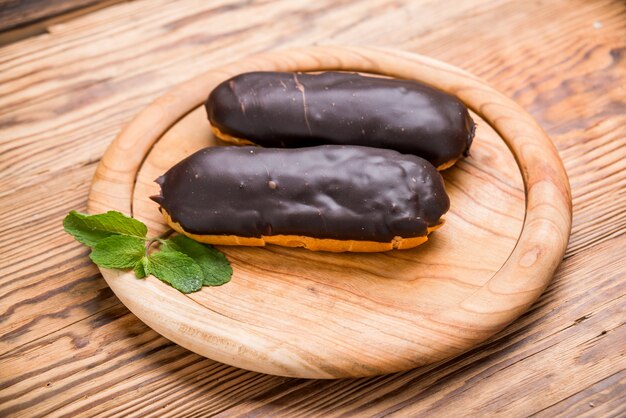 Eclairs sabrosos en mesa de madera