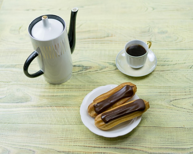 Eclairs und Kaffee auf einem hölzernen Hintergrund