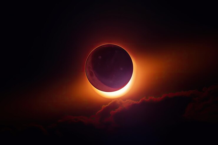 Foto eclipse solar com o sol parcialmente coberto pela lua lançando uma tonalidade avermelhada no céu
