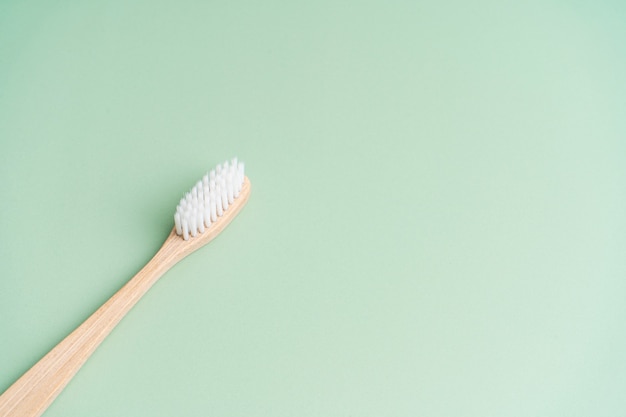 Eco amigável saúde dental antibacteriana bambu escova de dentes de madeira sobre fundo verde.