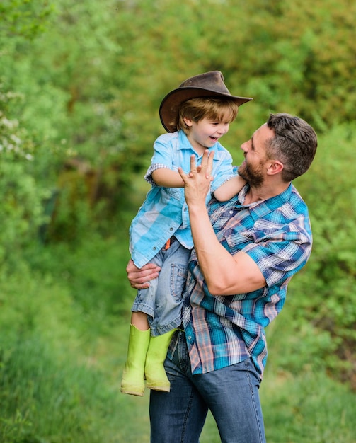 Eco fazenda menino criança ajuda pai na agricultura pai e filho com chapéu de cowboy no rancho garoto em botas de borracha homem feliz pai na floresta dia da família humana e natural feliz dia da terra família feliz