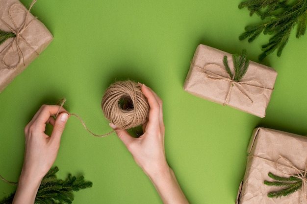 Foto eco guita nas mãos e presentes com plantas verdes em papel ofício na superfície verde