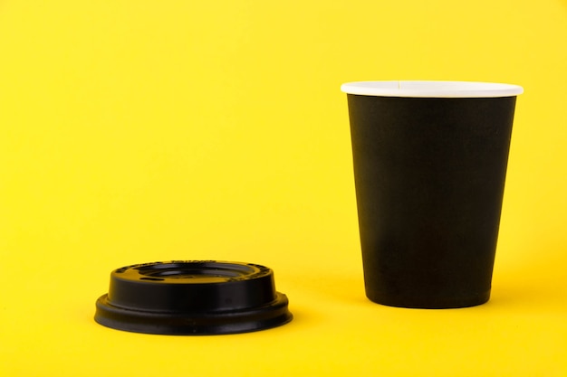 Eco schwarzer Pappbecher, Kaffee-Pappbecher auf gelbem Hintergrund. Mockup für Ihre Werbung. Platz kopieren.