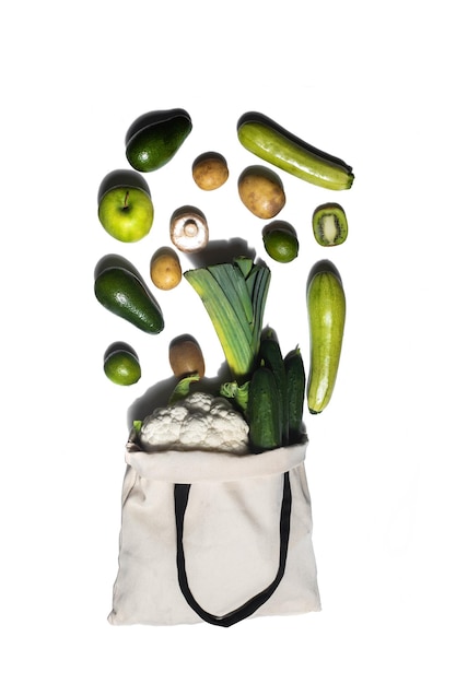 Ecobag llenando con verduras y frutas sobre fondo blanco.