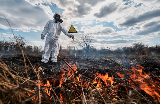 Ecologista bombeiro com máscara de gás trabalhando em campo com incêndios florestais