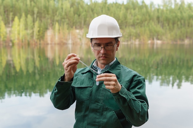 Ecologista industrial ou químico coleta uma amostra de água de um lago no local de uma pedreira inundada
