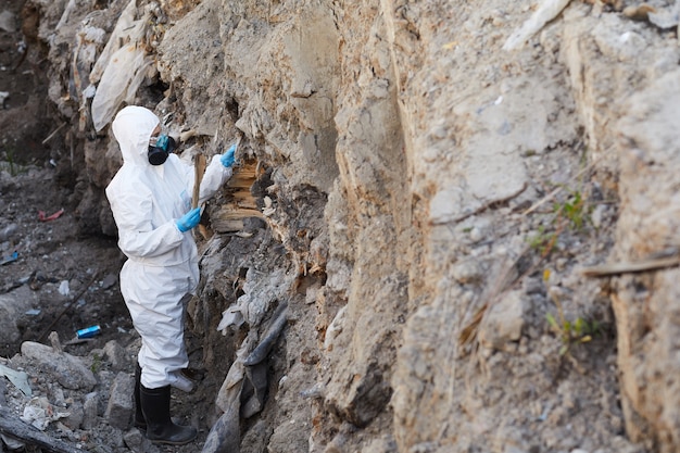 Ecologista en traje protector examinando las muestras de rocas en la naturaleza