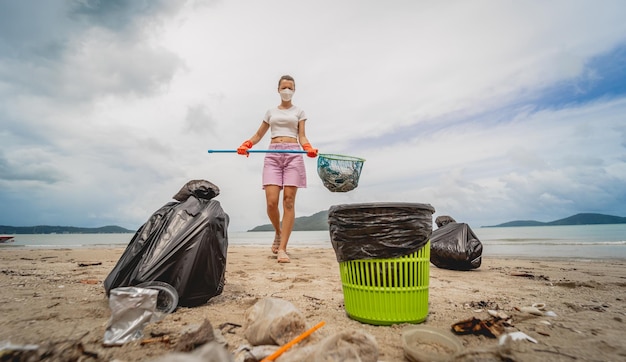 Una ecologista voluntaria limpia la playa a la orilla del mar de plástico y otros desechos