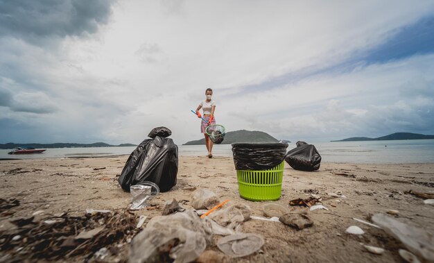 Una ecologista voluntaria limpia la playa a la orilla del mar de plástico y otros desechos