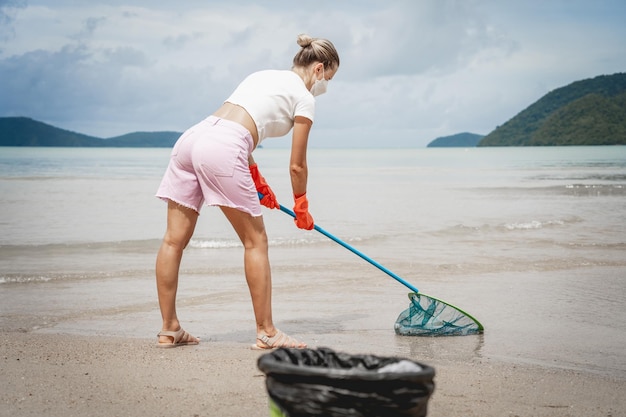 Una ecologista voluntaria limpia la playa a la orilla del mar de plástico y otros desechos