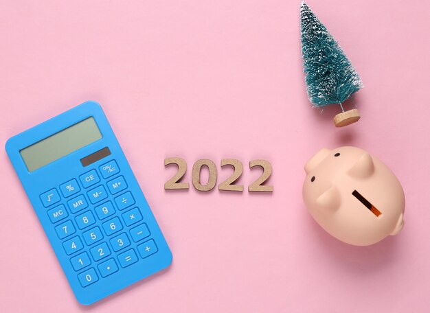 Economia e orçamento 2022 calculadora árvore de natal e cofrinho em fundo rosa