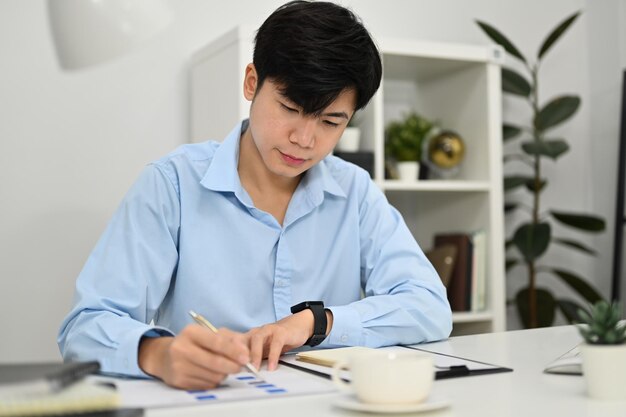 Economista profesional enfocado usando calculadora y revisando informes financieros en escritorio de oficina blanco