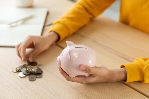 Economizando dinheiro para futuras mãos femininas segurando o cofrinho rosa e colocando moedas de dinheiro