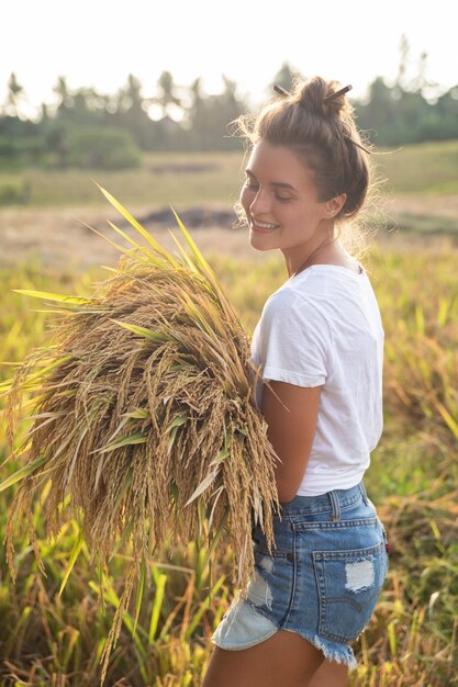 Ecoturismo ou trabalho diário. Mulher agricultora feliz durante a colheita no campo de arroz