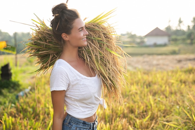 Ecoturismo ou trabalho diário. Mulher agricultora feliz durante a colheita no campo de arroz