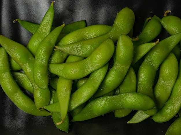 El edamame en un plato negro por concepto de comida