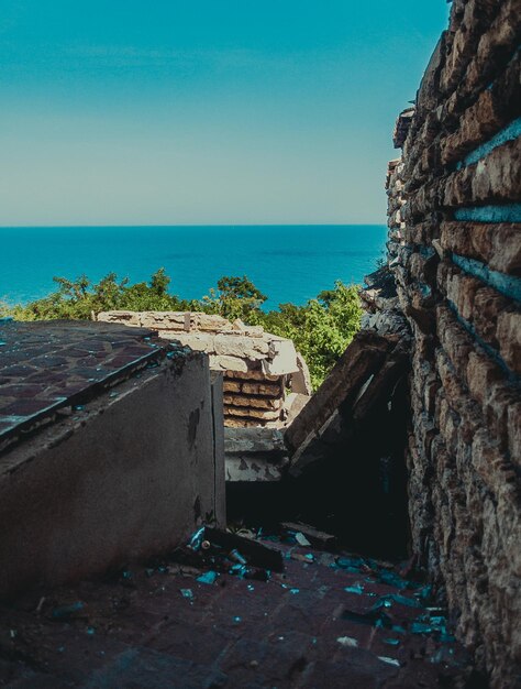 Foto edifício abandonado ao lado do mar contra o céu azul claro