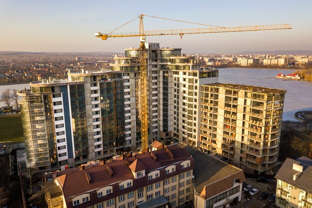 Edificio alto de apartamentos u oficinas en construcción, vista superior. Grúa torre y paisaje de la ciudad que se extiende hasta el horizonte. Drone fotografía aérea.