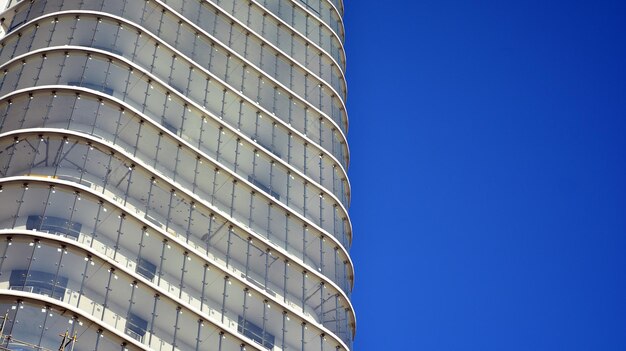 Un edificio alto de cristal con un cielo azul detrás