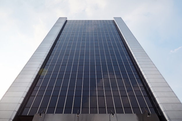 Edificio alto con ventanas de espejos oscuros contra el cielo.