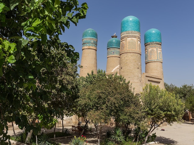 Edifício antigo Chor Minor Madrassah com minaretes contra o céu azul claro Bukhara Uzbequistão