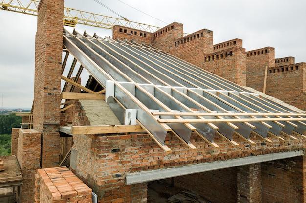 Edificio de apartamentos de ladrillo sin terminar con estructura de techo de madera en construcción.