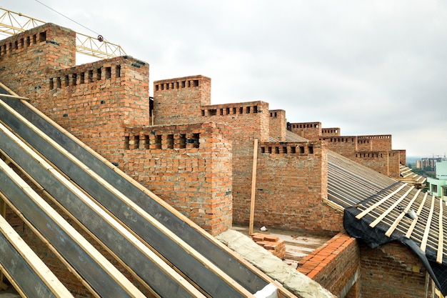 Edificio de apartamentos de ladrillo sin terminar con estructura de techo de madera en construcción.