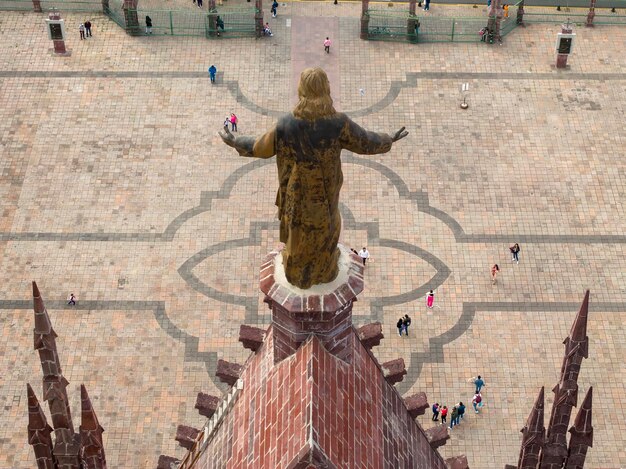 Foto edifício com uma estátua e pessoas a caminhar