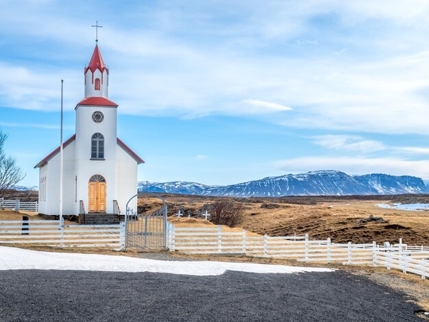Edifício de arquitetura clássica da igreja de Helgafell da igreja da islândia na colina na temporada de inverno sob céu azul nublado