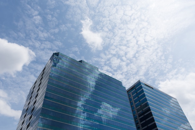 Edifício de escritórios de vidro grande com céu azul e nuvem branca