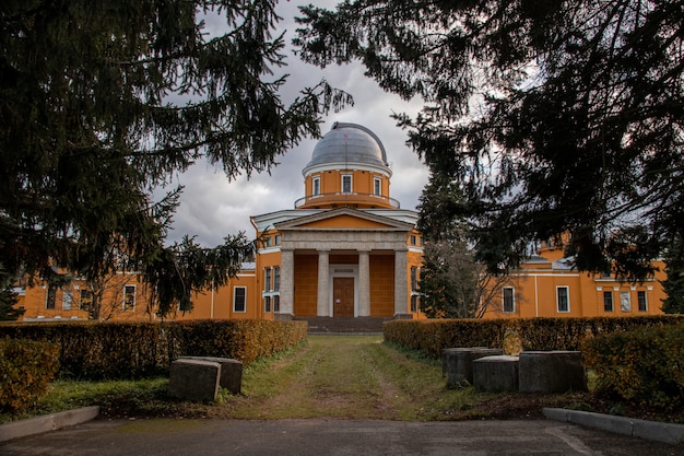 Edifício de observatório laranja atrás de abetos no parque