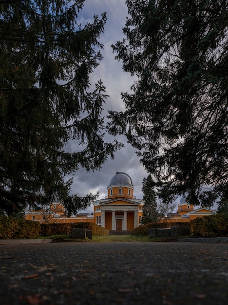 Edifício de observatório laranja atrás de abetos no parque