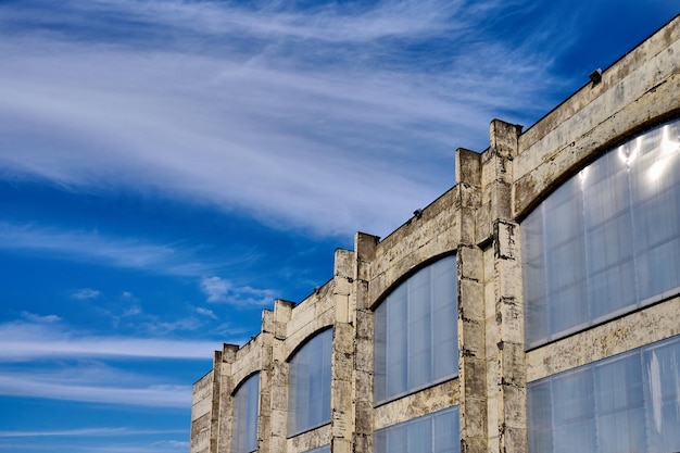 Edifício do antigo pavilhão de produção abandonado com janelas fechadas com lonas de plástico contra o