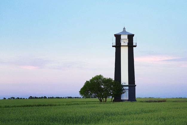 Edifício do farol. Edifício antigo farol preto e branco fica em terreno no campo ao pôr do sol no verão.