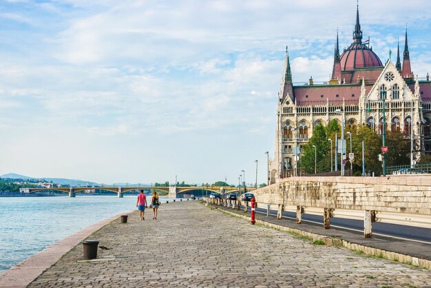Edifício do Parlamento húngaro e pessoas na margem do Rio Danúbio em Budapeste, Hungria