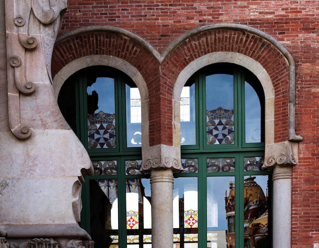 Foto un edificio con dos ventanas arqueadas con adornos verdes.