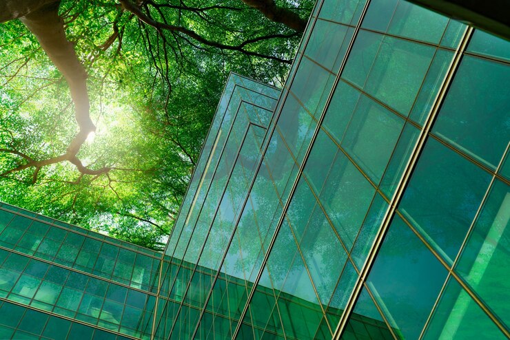 Foto edifício ecológico na cidade moderna. galhos de árvores verdes com folhas e construção de vidro sustentável para reduzir o calor e o dióxido de carbono. prédio de escritórios com ambiente verde. vá o conceito verde.