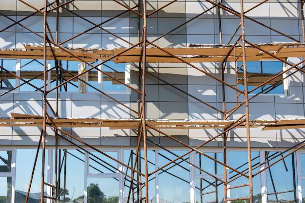 Edifício em construção Fragmento de andaime contra a parede da casa Casas residenciais em construção