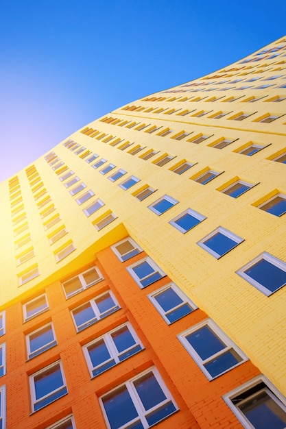 Edificio europeo moderno de varios pisos con muchas ventanas de vidrio de pie contra el fondo del cielo azul y el sol. Edificios residenciales, urbano, bienes raíces colección de foto
