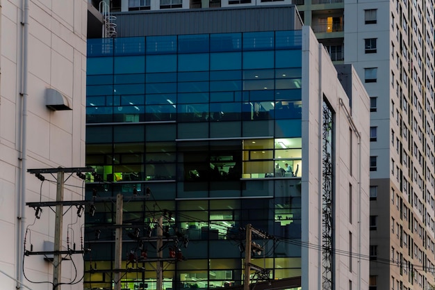 Un edificio de gran altura con una fachada de vidrio y un poste eléctrico en primer plano Un hombre de negocios está de pie en una oficina