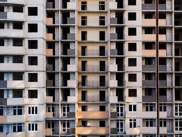 Edificio inacabado de varios pisos. edificio de ladrillo en construcción de gran altura, andamio, montacargas,