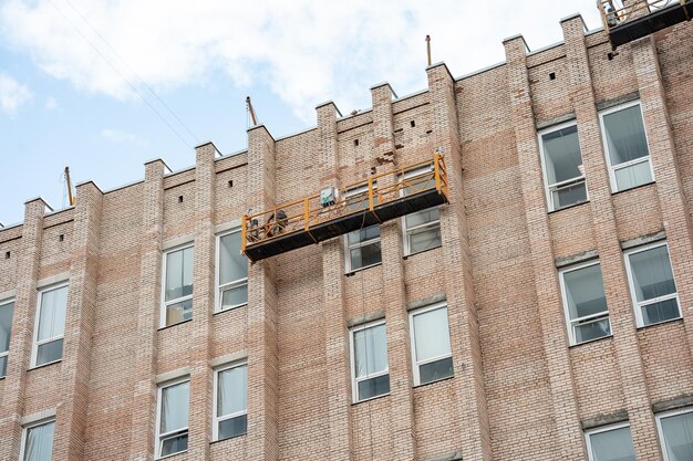 Foto un edificio de ladrillo con un andamio amarillo a un lado.