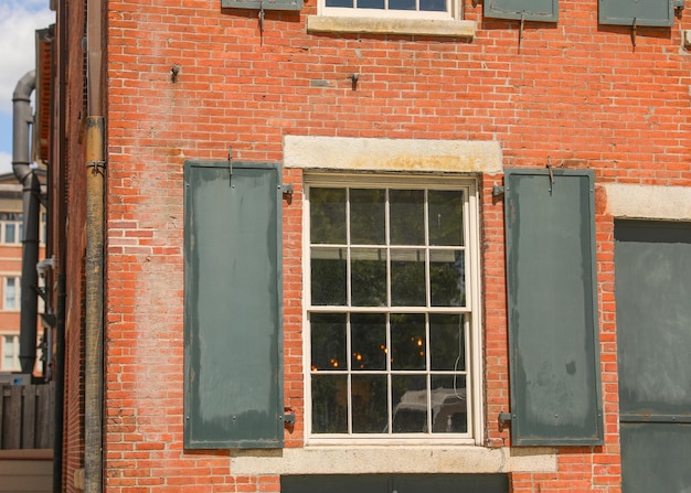 Un edificio de ladrillo rojo con una ventana con persianas verdes.