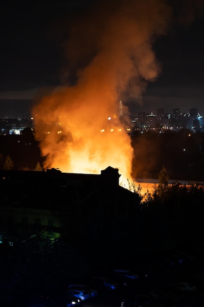 Edificio en llamas por la noche llamas anaranjadas y humo denso sobre la ciudad