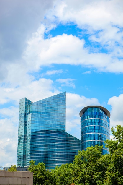 Edificio moderno cerca del parque con árboles verdes contra el cielo azul