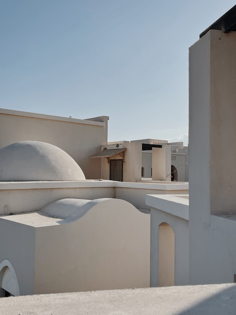 Edifício moderno de estilo oriental com paredes bege, janelas e sombras de luz solar